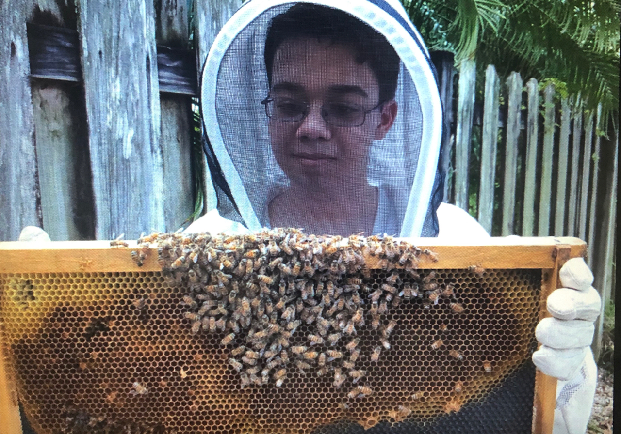 A photo of a photo of me holding a Hive Frame while wearing a beekeeper suit.